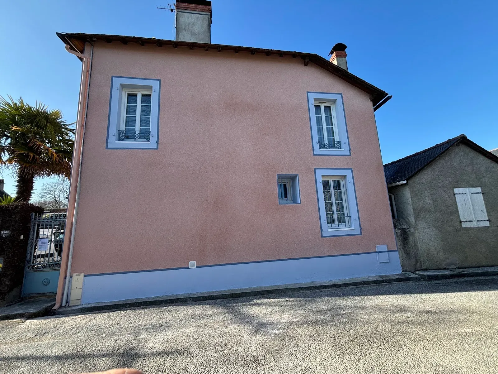 Façade de maison ravalée, enduit saumon et volets bleus