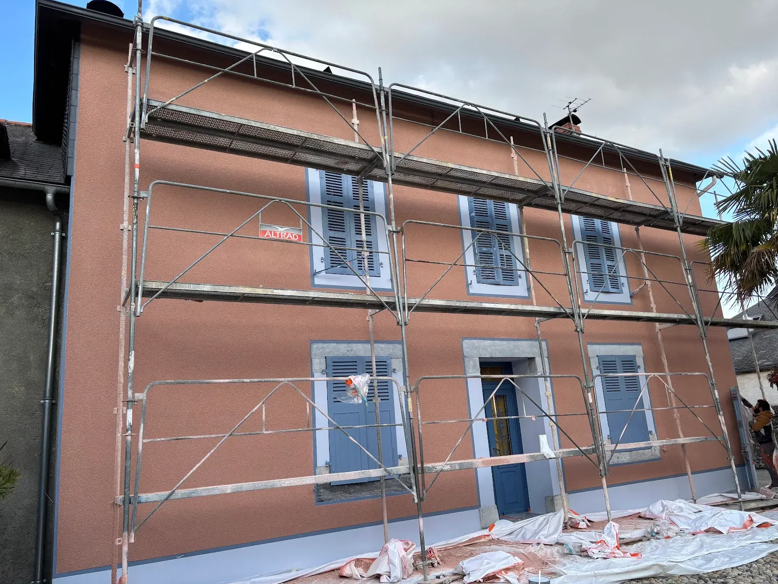 Façade de maison en cours de ravalement, enduit appliqué sous échafaudage
