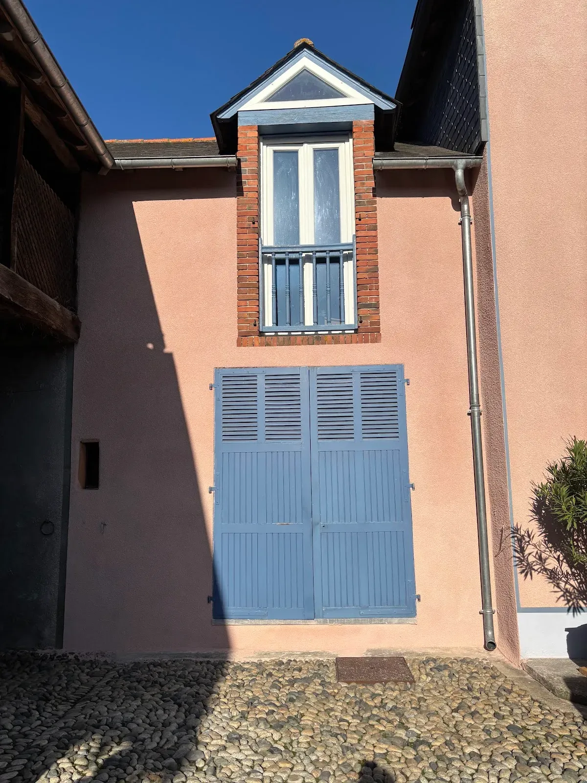 Détail d’une lucarne en brique et de volets bleus